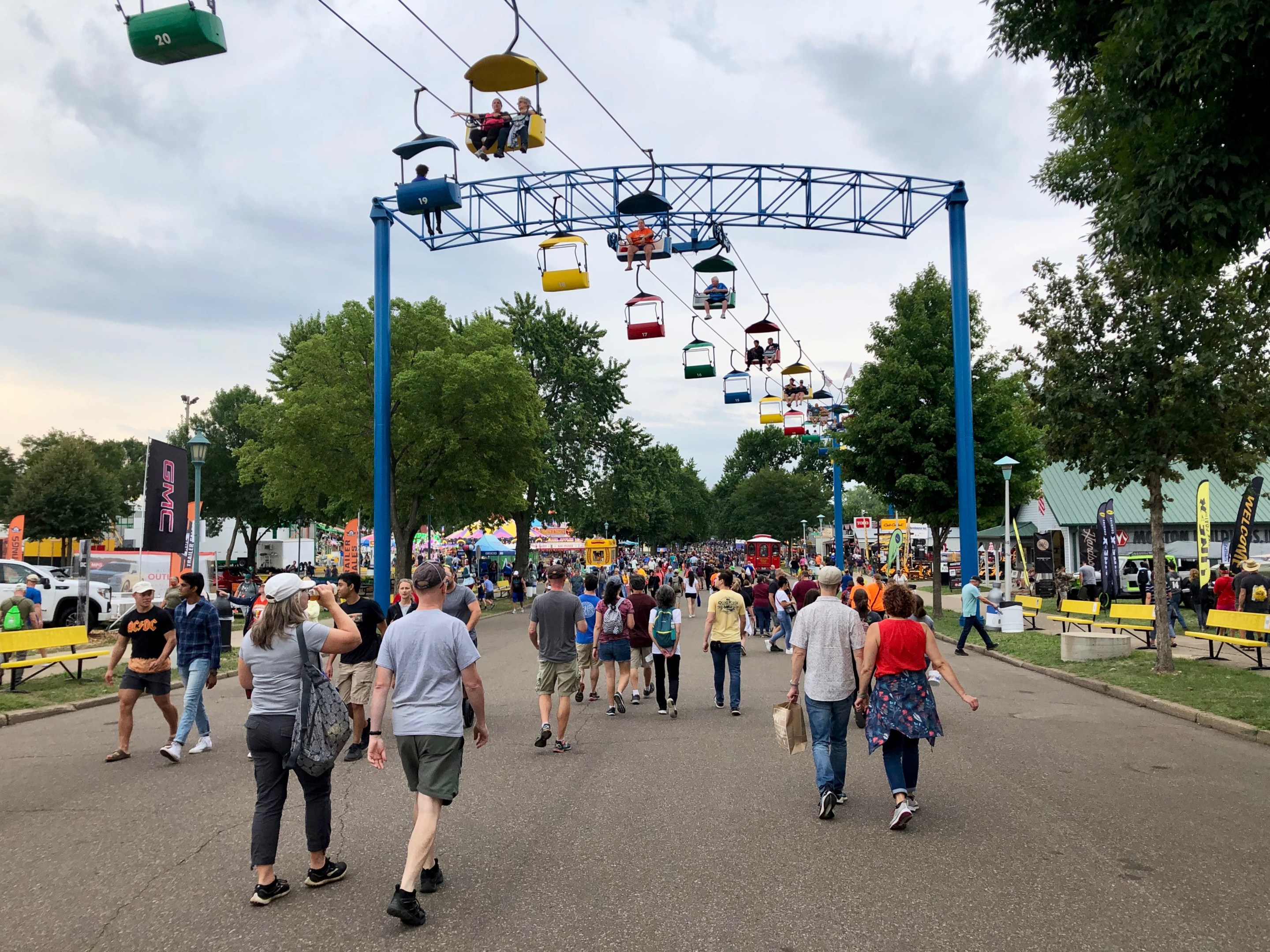 people walk below the sky ride at the state fair