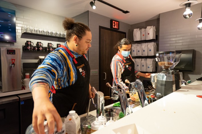 two baristas prepare coffee behind the get down counter