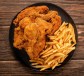 an overhead shot of a platter of fried chicken and french fries on a wooden table