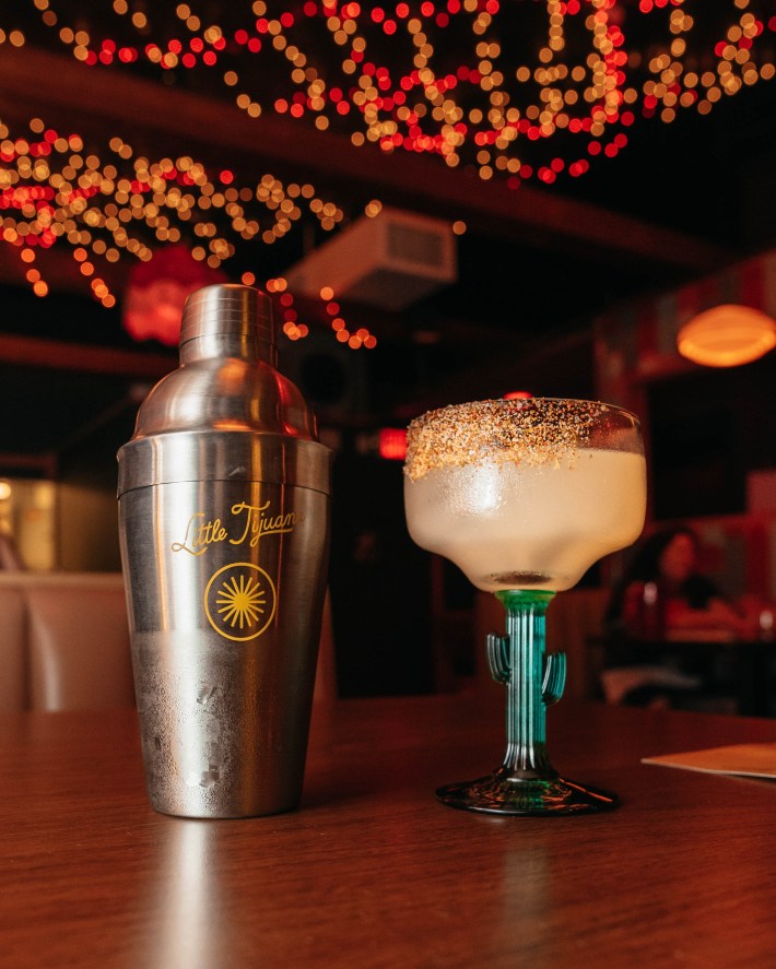 a little tijuana cocktail shaker next to a margarita served in a cactus glass