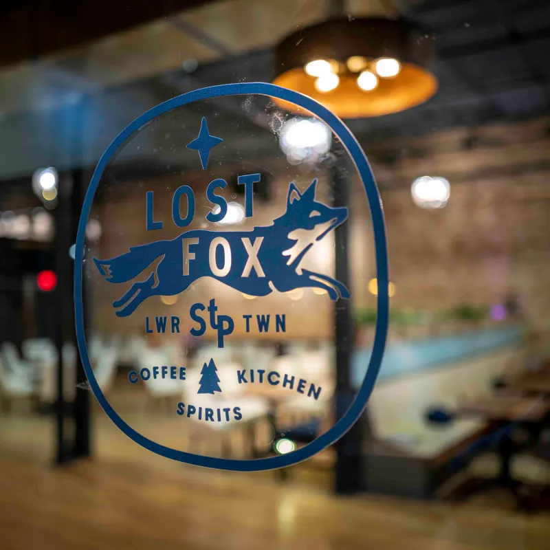 photo of the front door of lost fox, with a little blue fox jumping in the air