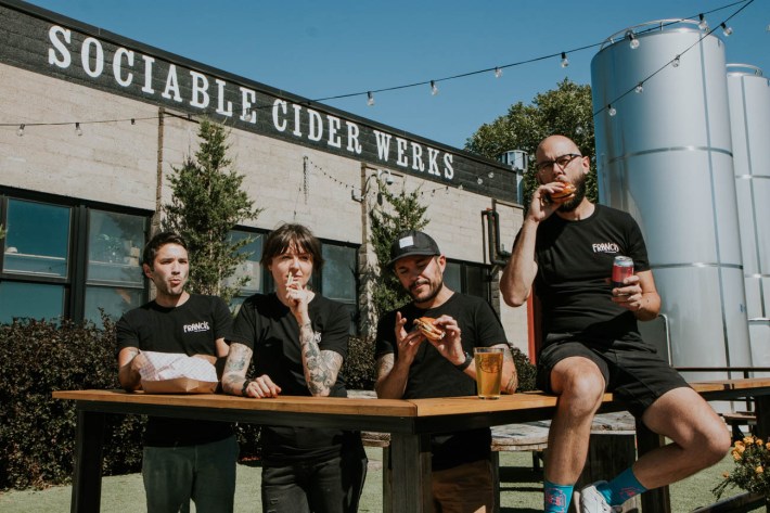 four people sit at a table outside sociable cider werks eating (vegan) burgers