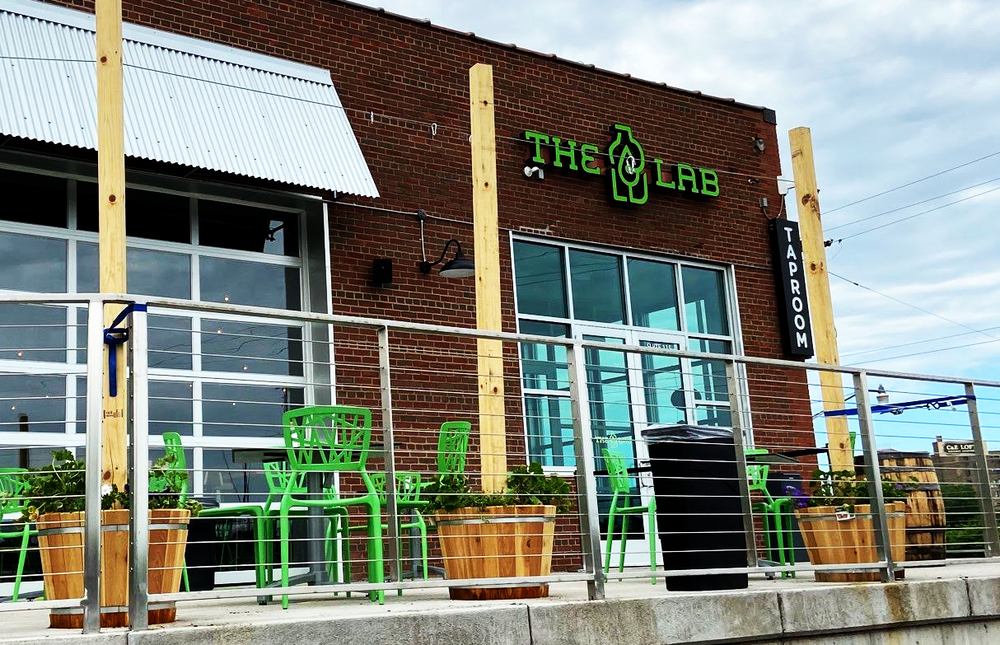 exterior shot of the lab building in st. paul, a brick space with bright-green chairs that match the bright-green sign
