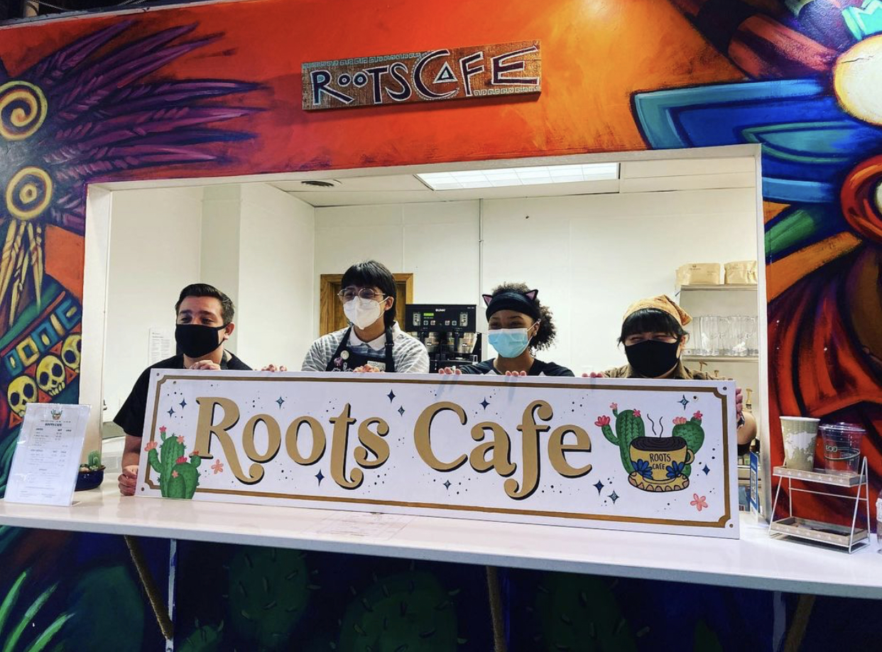 four youth workers stand in the colorful red and orange roots cafe space