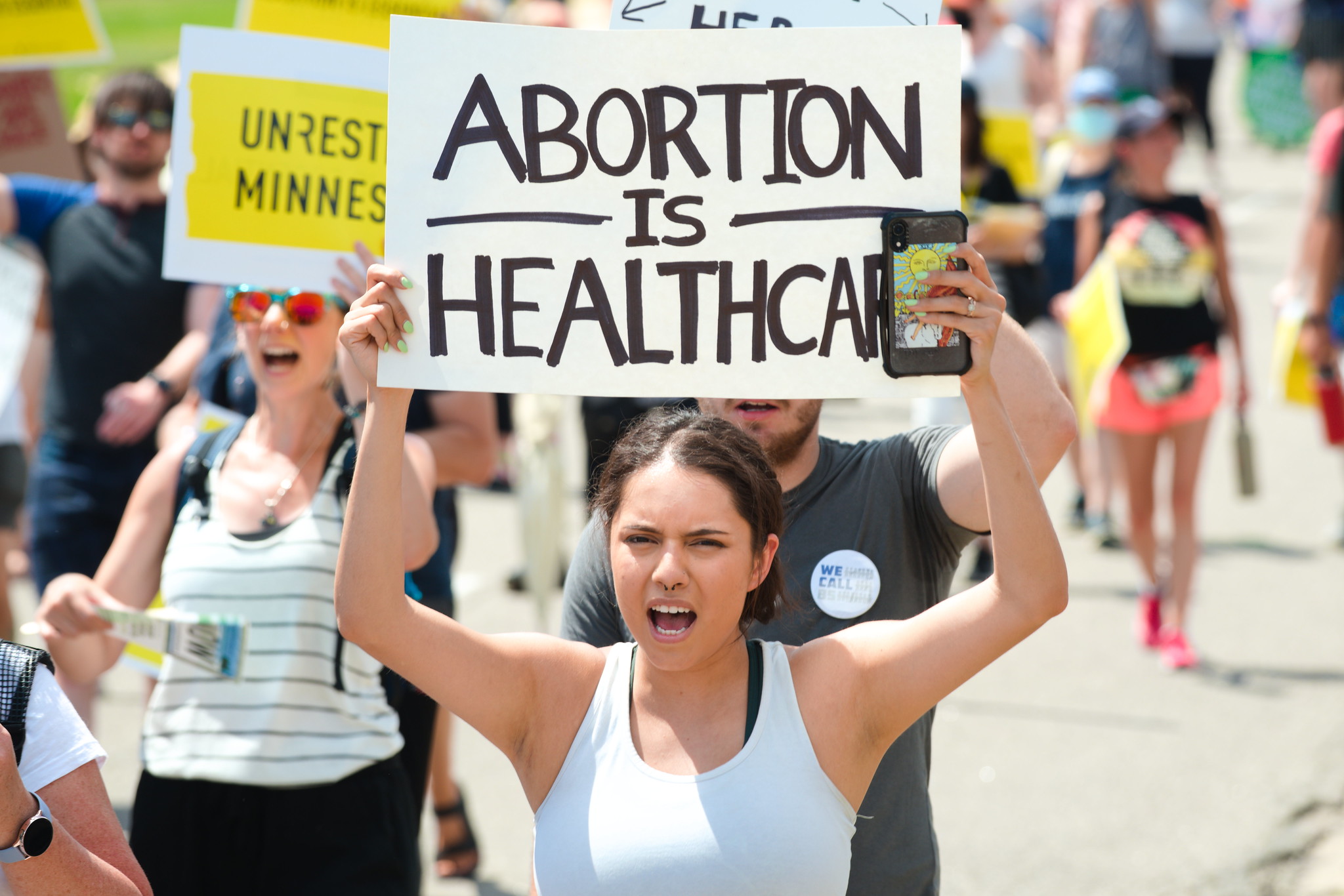 a person holds an "abortion is healthcare" sign during an MN abortion rally