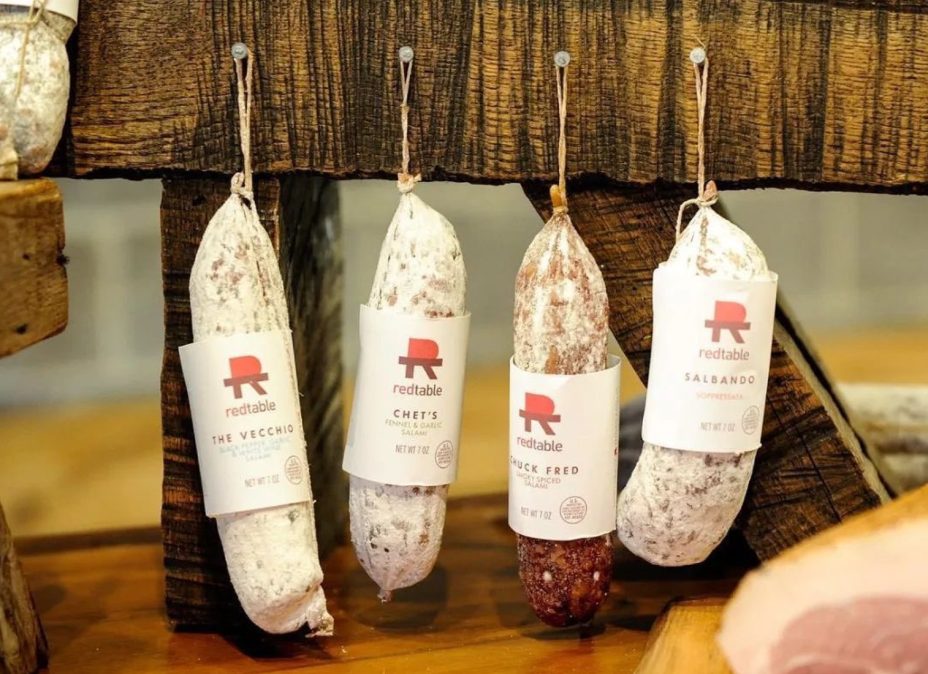 four red table salamis hanging from a wooden beam