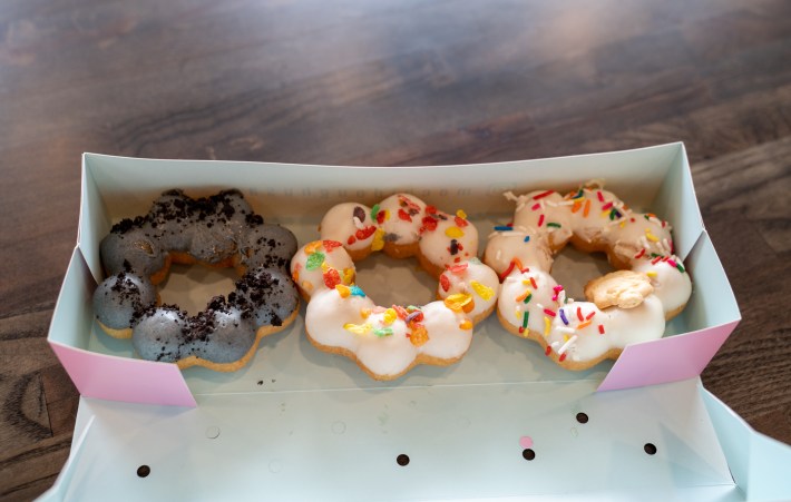 three colorful mochi dough donuts in a pink box