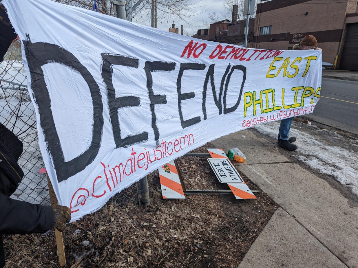 protesters hold a huge handpainted "defend east phillips" banner