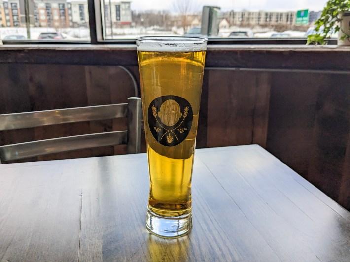 a glass of beer on a table near a window