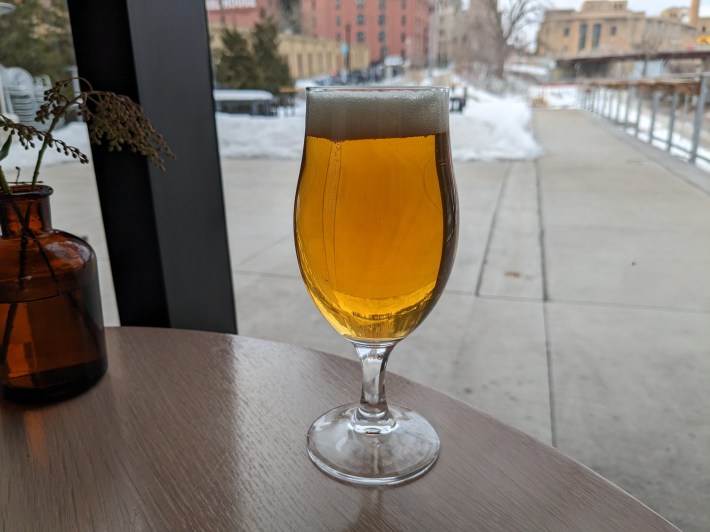 a glass of beer on a table near a window
