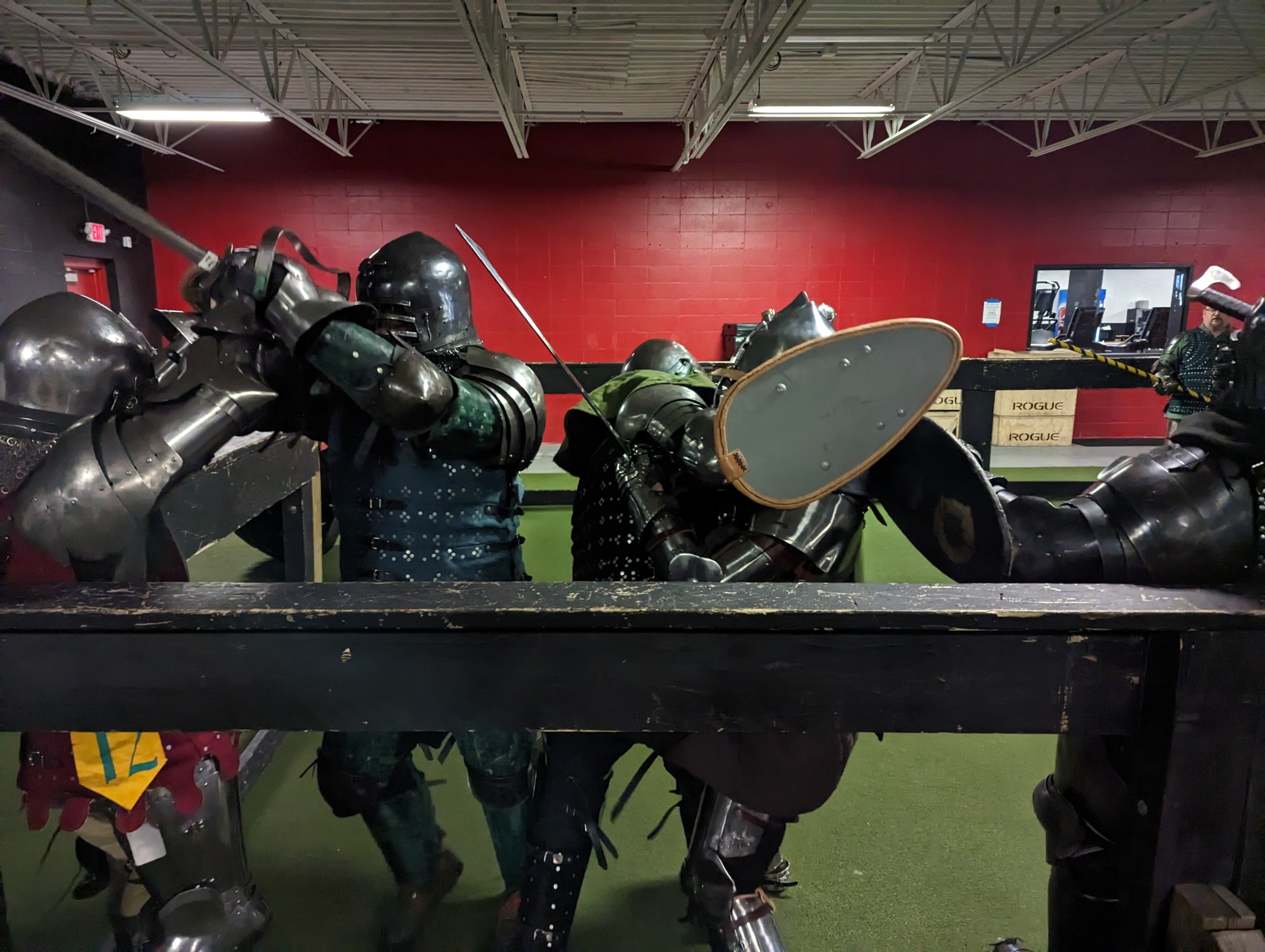 A group of people in full suits of armor swing at each other with swords and shields. They're at a gym in St. Paul, and this is taking place on fake turf.