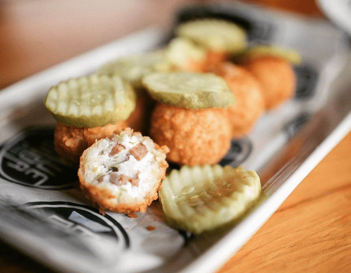 A platter of round, fried spam bites, with one cut open to reveal the cream cheese and spam center within